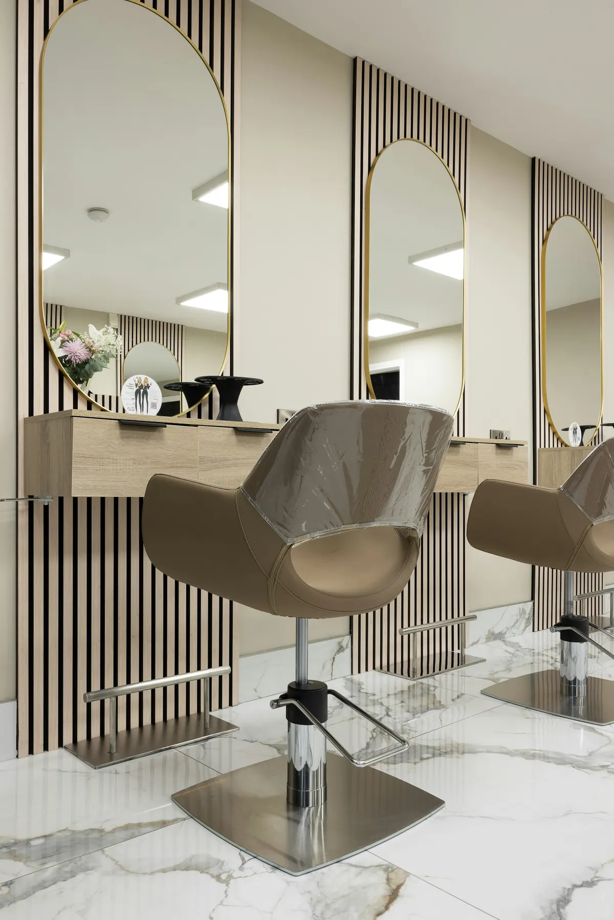Elegant salon with arched mirrors, styling chairs, and marble floors