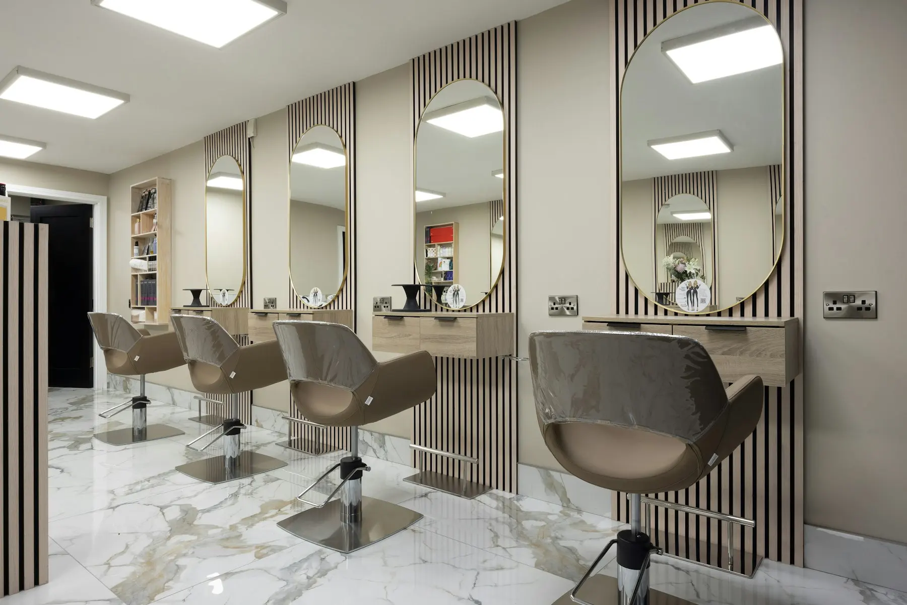Bright salon with styling chairs, slatted wood panels, and marble floors